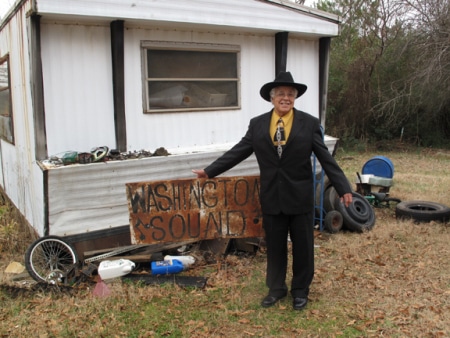 David Lee with the Washington Sound record shop sign, in front of his storage trailer.